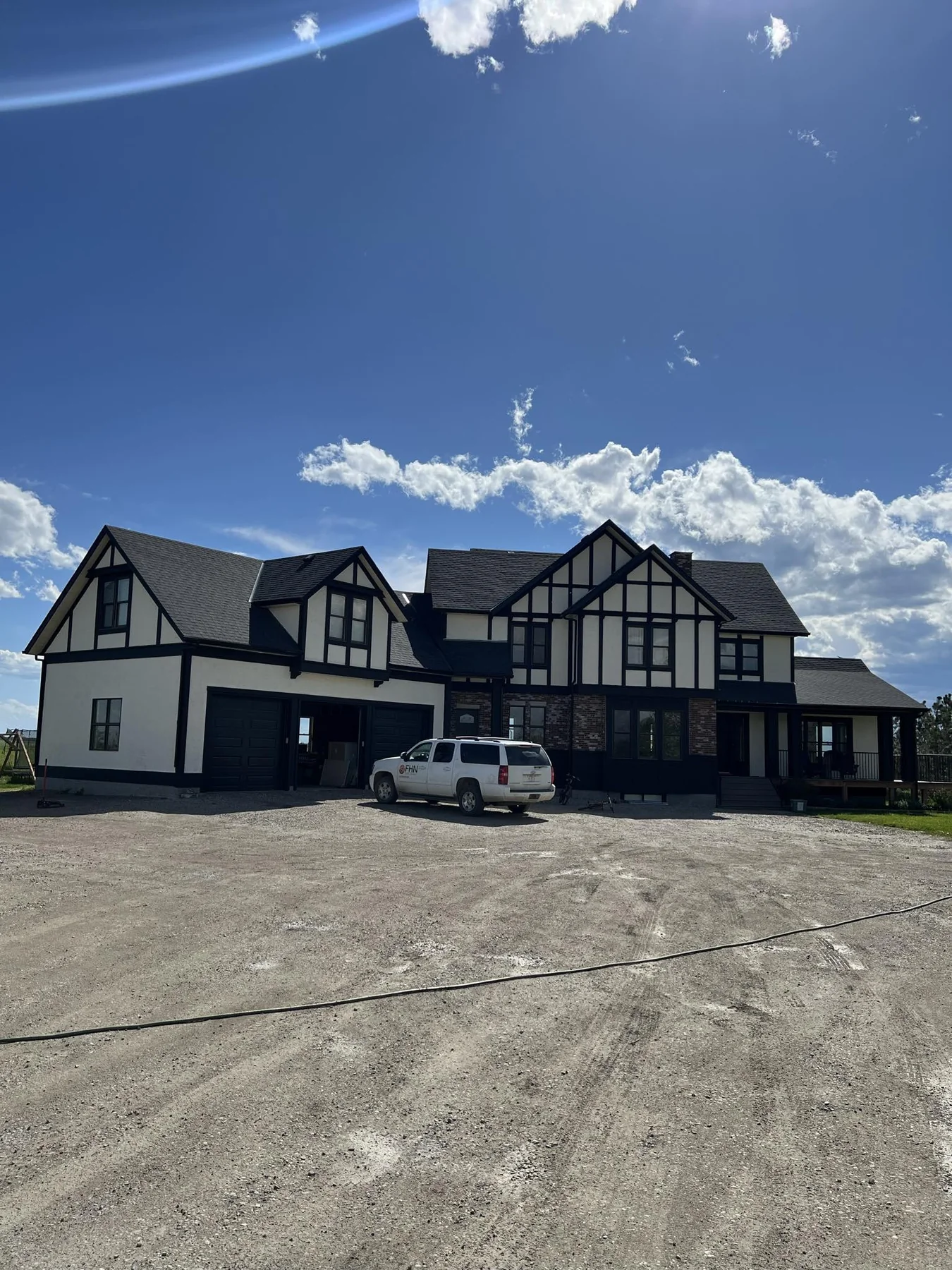 Large black and white stucco estate with dramatic dark trim and Tudor-inspired exterior detailing